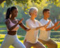 Drei Menschen üben Qi-gong in einem sonnigen Park aus.